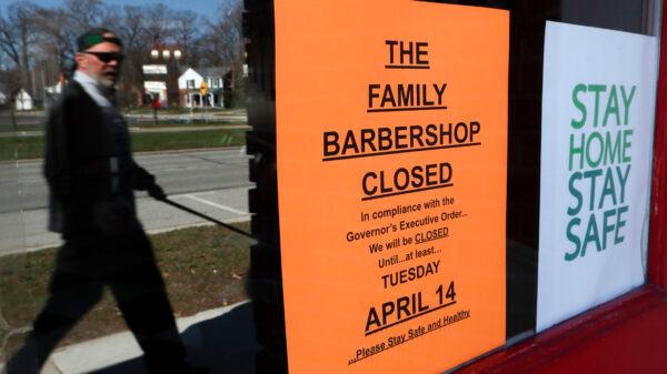 A pedestrian walks by The Family Barbershop, closed due to a Gov. Gretchen Whitmer executive order, in Grosse Pointe Woods, Mich. on April 2, 2020. (AP Photo/Paul Sancya)
