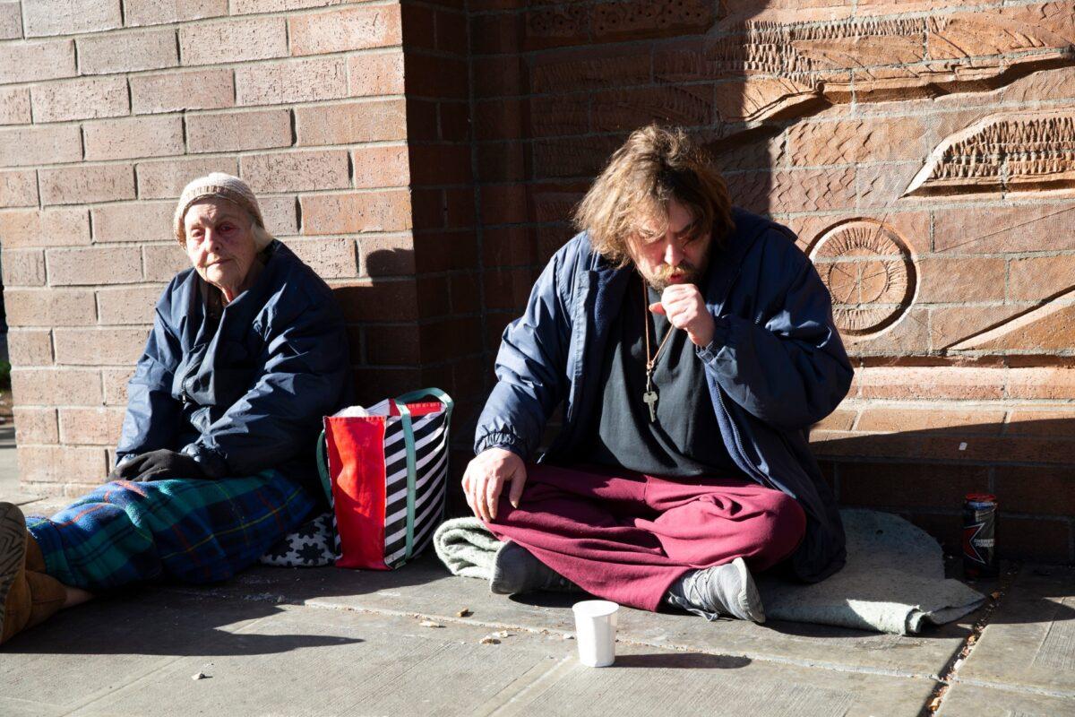 James Deane (R) has a bad cough but he and friend Marla (no last name given) say they feel alright as they sit on the sidewalk in Seattle, Washington, on April 6, 2020. (Karen Ducey/Getty Images)