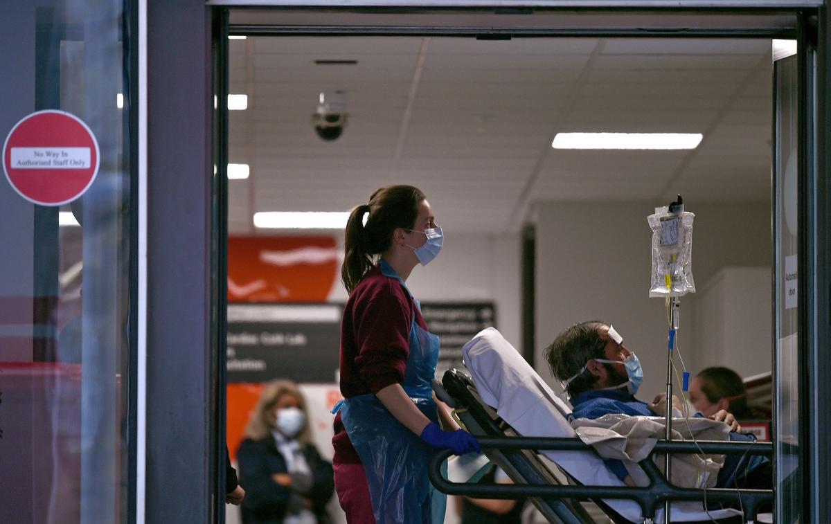 A healthcare worker pushes a patient, both wearing masks, inside St Thomas' Hospital in London, England, on April 1, 2020. (©Getty Images | <a href="https://www.gettyimages.com/detail/news-photo/medical-professional-in-ppe-including-gloves-an-apron-and-a-news-photo/1208880278?adppopup=true">DANIEL LEAL-OLIVAS</a>)