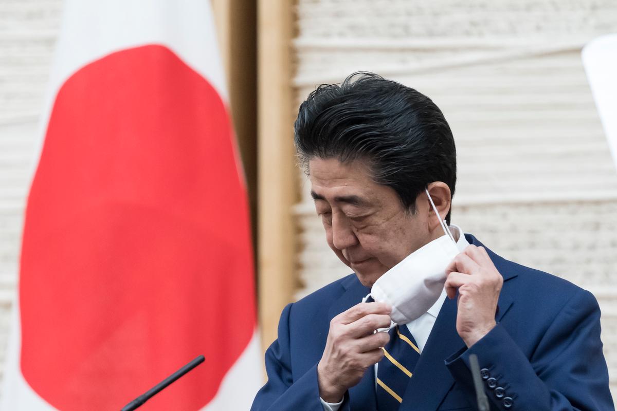 Japan's Prime Minister Shinzo Abe removes his protective mask during a press conference in Tokyo, Japan, on April 7, 2020. (Tomohiro Ohsumi/Getty Images)