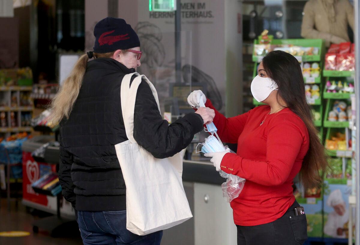Supermarket employees distribute masks to customers in Vienna on April 1, 2020. (Ronald Zak/AP Photo)