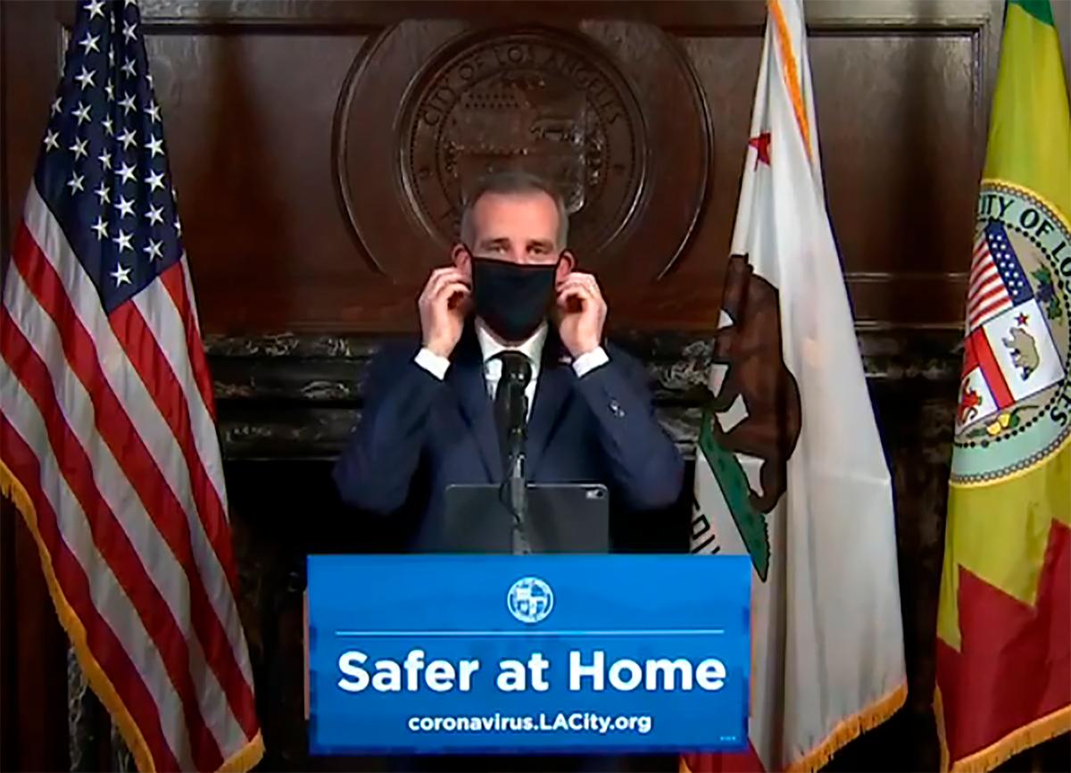 Los Angeles Mayor Eric Garcetti displays putting on a protective face mask during his daily news conference in Los Angeles on April 1, 2020. (Office of Mayor Eric Garcetti via AP)