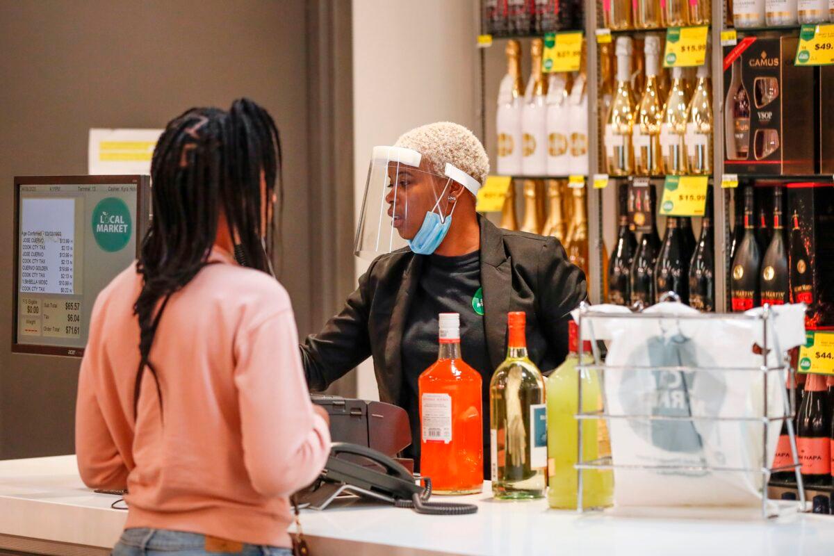 An employee wearing a mask rings up a customer's alcohol purchase at the Local Market Foods store in Chicago, Illinois, on April 8, 2020. (Kamil Krzaczynski/AFP via Getty Images)