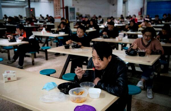 Workers eating at lunch break after making hazardous material suits to be used in the COVID-19 coronavirus outbreak, at the Zhejiang Ugly Duck Industry garment factory in Wenzhou, China, on Feb. 28, 2020. (Noel Celis/AFP via Getty Images)