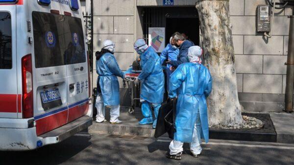 Medical staff in protective clothes are seen carrying a patient from an apartment suspected of having the CCP virus in Wuhan, in Hubei province on Jan. 30, 2020. (Hector Retamal/AFP via Getty Images)