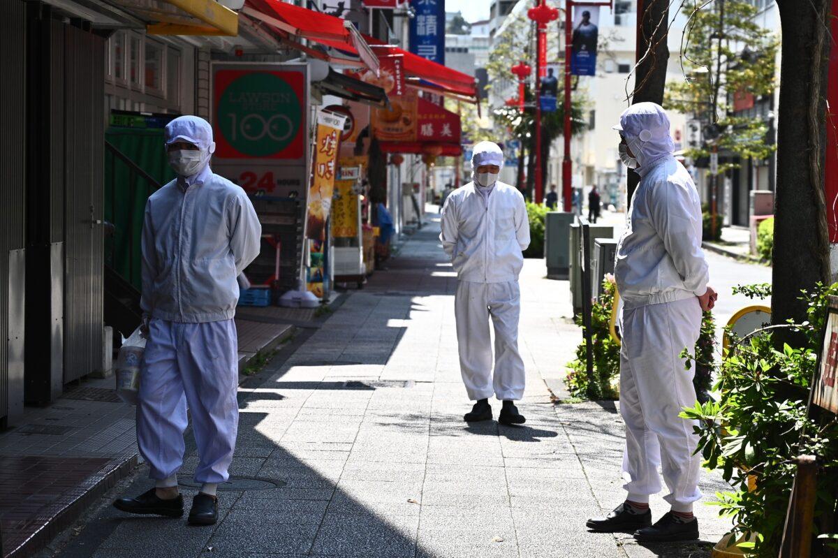 Employees of a restaurant wearing masks stand outside their eatery before it opens in the Chinatown area in Yokohama on April 9, 2020. (Philip Fong/AFP via Getty Images)