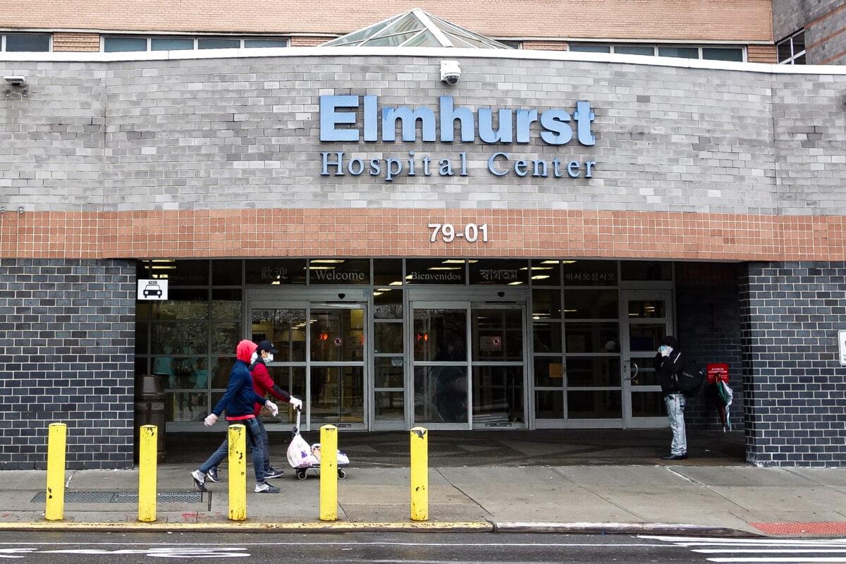 People wear masks as they walk outside the Elmhurst Hospital Center in Elmhurst, Queens, New York on March 29, 2020. (Chung I Ho/The Epoch Times)