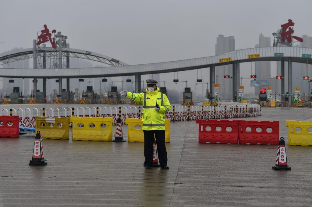 An officer gestures in front of one of the roads blocked by the police to restrict people leaving Wuhan in China's central Hubei province on January 25, 2020, during a deadly virus outbreak which began in the city. (©Getty Images | <a href="https://www.gettyimages.com/detail/news-photo/an-officer-gestures-in-front-of-one-of-the-roads-blocked-by-news-photo/1196080723">Hector RETAMAL / AFP</a>)