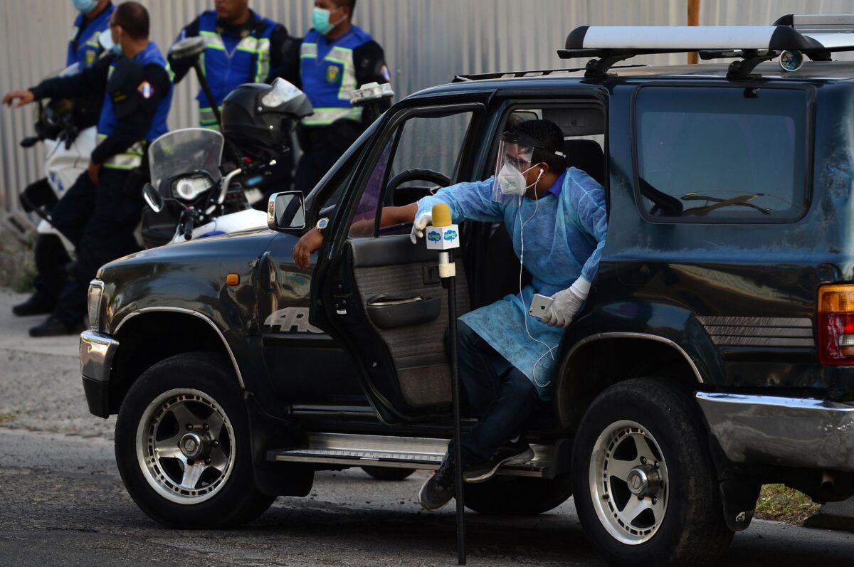A journalist wears a protective outfit against the spread of COVID-19 as he waits for the arrival of the remains of Honduran former president Rafael Leonardo Callejas from Atlanta, USA, at the Air Force base in Tegucigalpa, on April 9, 2020. (Orlando Sierra/AFP/Getty Images)