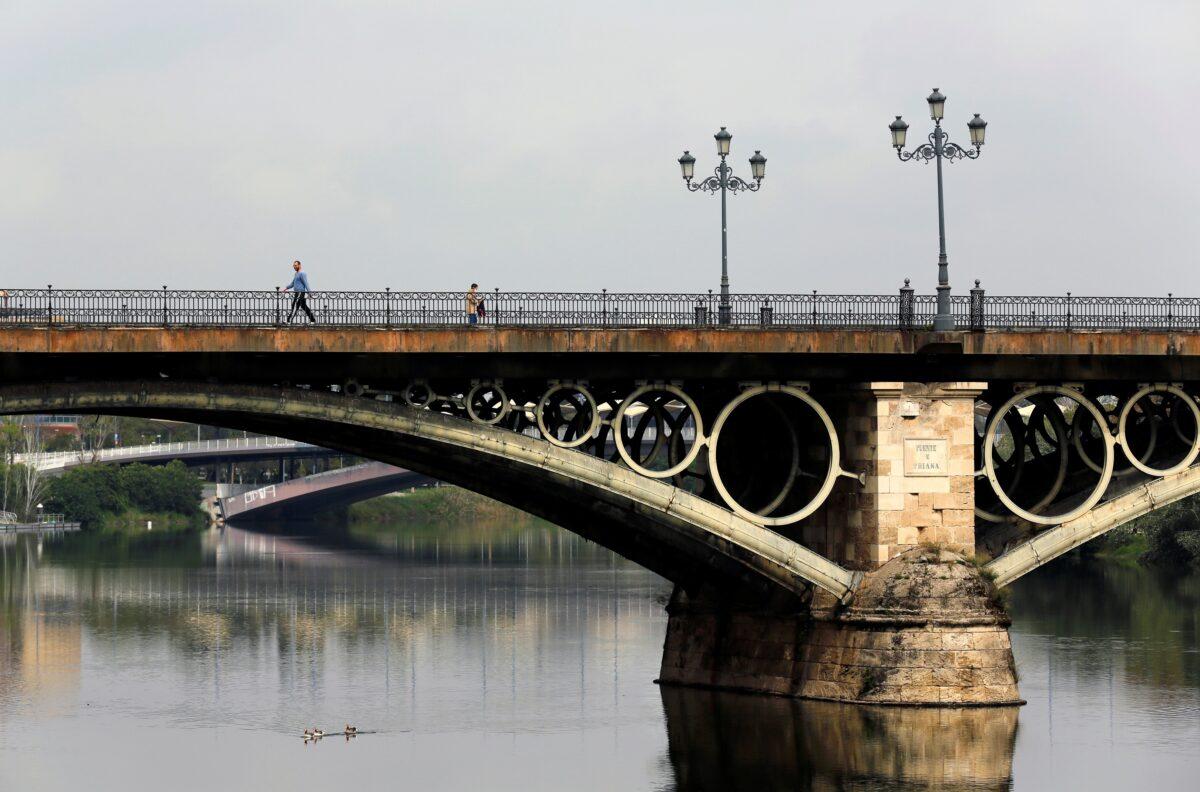 People walk along Triana bridge during the CCP virus outbreak in the Andalusian capital of Seville, Spain, on April 10, 2020. (Marcelo del Pozo/Reuters)