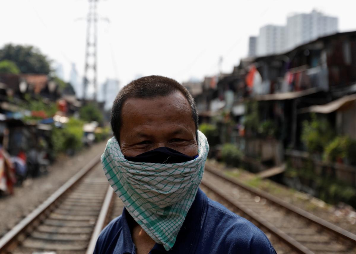 A man covers his face with a napkin along rail tracks, during the large-scale social restrictions to prevent the spread of the CCP virus in Jakarta, Indonesia, on April 12, 2020. (Willy Kurniawan/Reuters)