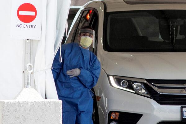 A frontline healthcare worker attends people at the Etobicoke General Hospital drive-thru COVID-19 assessment centre, in Toronto, Ontario, Canada, on April 9, 2020. (Carlos Osorio/Reuters)