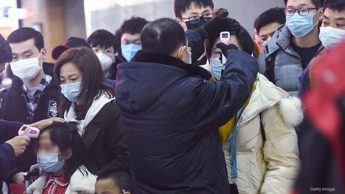 Staff members (in black) check the body temperature of passengers after a train from Wuhan arrived at Hangzhou Railway Station in Hangzhou, China's eastern Zhejiang province, in a file photograph. (AFP via Getty Images)