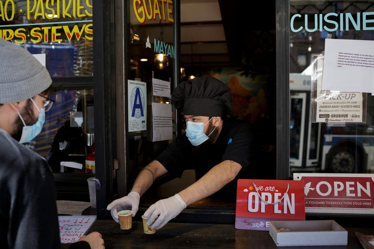 Chef and part-owner Jorge Cardenas, 41, hands customers free shots of broth while they wait for their takeout order outside of Ix restaurant in the Brooklyn borough of New York City, U.S., on April 2, 2020. (Anna Watts/Reuters)