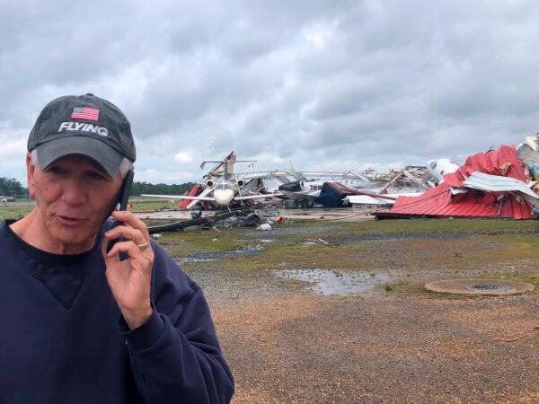In this photo provided by Rep. Ralph Abraham, R-La., he is seen talking on his phone in front of a destroyed hangar and damaged planes at Monroe Regional Airport in Monroe, La., on April 12, 2020. (Dianne Abrams via AP)