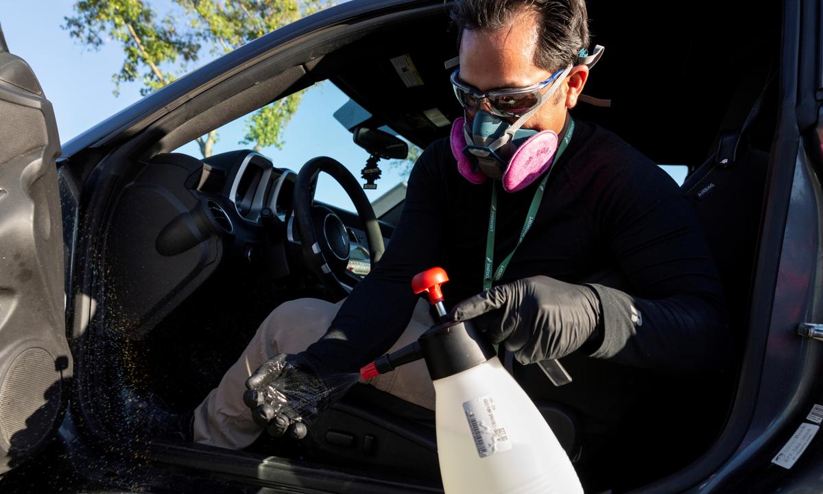 Instacart employee Eric Cohn, 34, sprays his gloves with disinfectant while wearing a respirator mask to help protect himself and slow the spread of the CCP virus disease in Tucson, Ariz., U.S. on April 4, 2020. (Cheney Orr/Reuters)