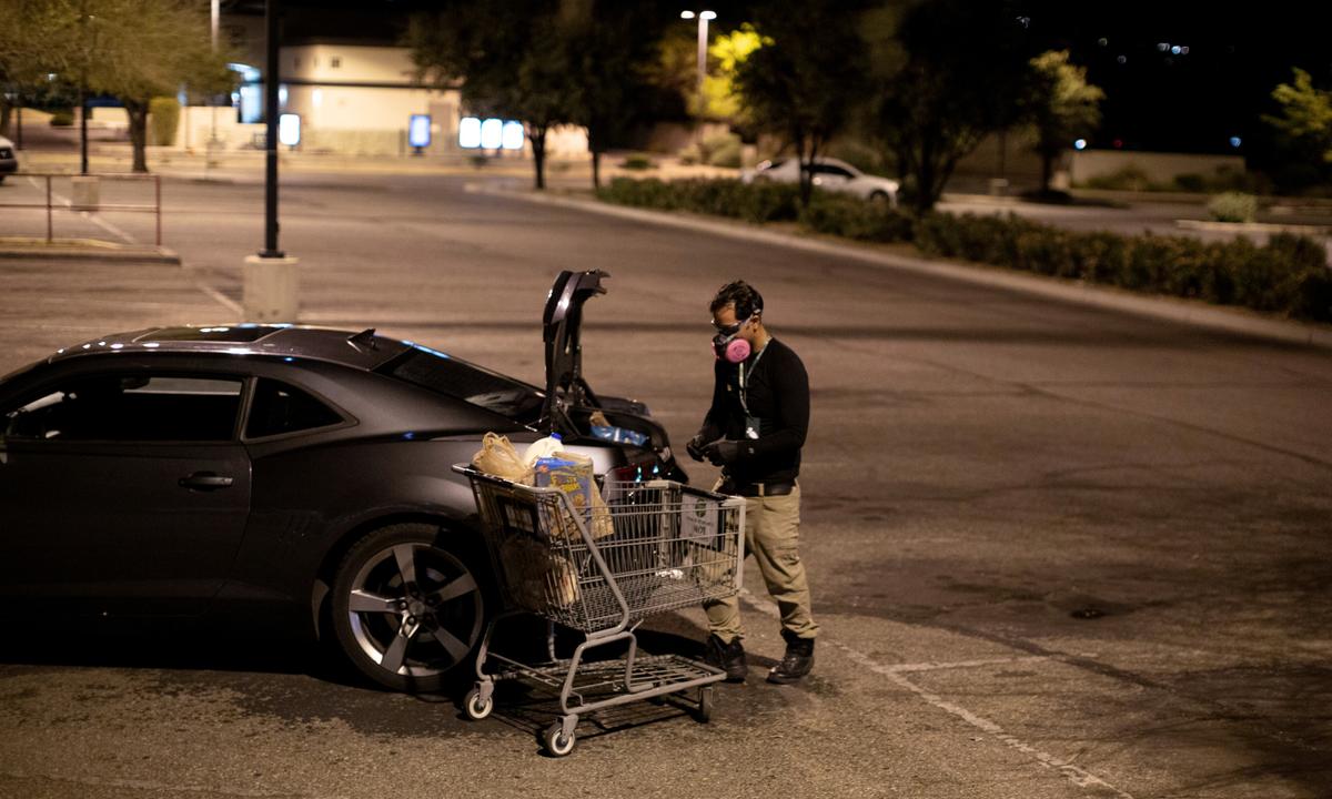 Instacart employee Eric Cohn, 34, loads an order into his car outside a Fry's grocery store while wearing a respirator mask to help protect himself and slow the spread of the CCP virus disease in Tucson, Ariz., U.S. on April 4, 2020. (Cheney Orr/Reuters)