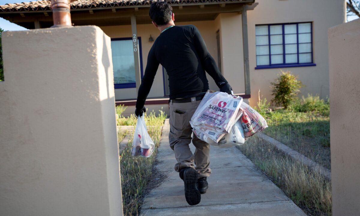 Instacart employee Eric Cohn, 34, delivers groceries to a residence while wearing a respirator mask to help protect himself and slow the spread of the CCP virus disease in Tucson, Ariz., on April 4, 2020. (Cheney Orr/Reuters)