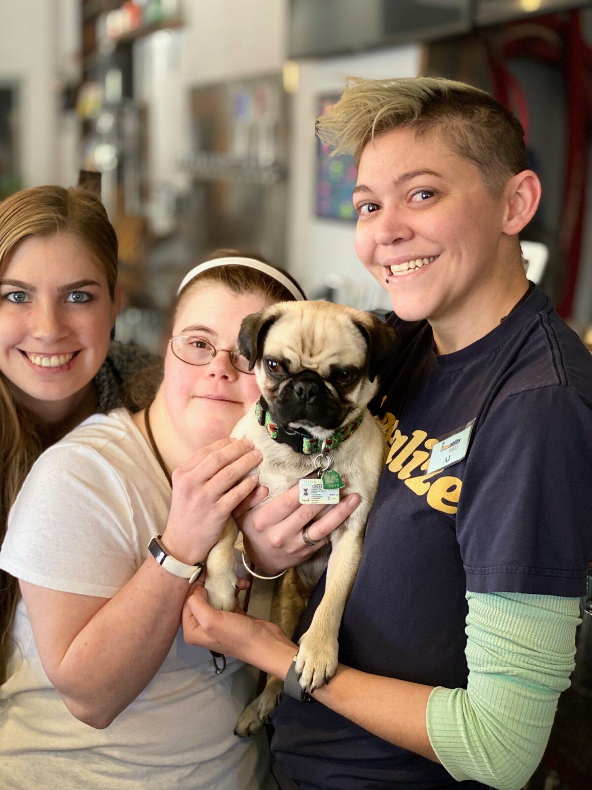 (L–R) Chelsea Whitaker, a certified occupational therapy assistant, Rachel Kurth, beertender, and AJ McCollum, manager, holding a pug for Guided by Humanity's Pug Yoga at Brewability. (<a href="https://www.facebook.com/guidedbyhumanity">www.facebook.com/guidedbyhumanit</a>y) (Courtesy of <a href="https://www.brew-ability.com/">Brewability Lab</a>)