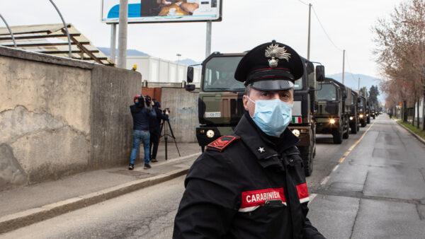 A Carabinieri officer blocks the road traffic as a convoy of military vehicles arrives at the Monumental Cemetery in Bergamo, near Milan, Italy, on March 26, 2020. (Emanuele Cremaschi/Getty Images)