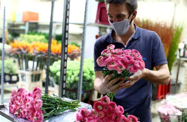 A seller wears a protective mask as he prepares flowers for sale at the central flower market (Grossgruenmarkt) during the partial reopening of stores after the Austrian government loosens its lockdown restrictions during the CCP virus outbreak in Vienna on April 14, 2020. (Lisi Niesner/Reuters)