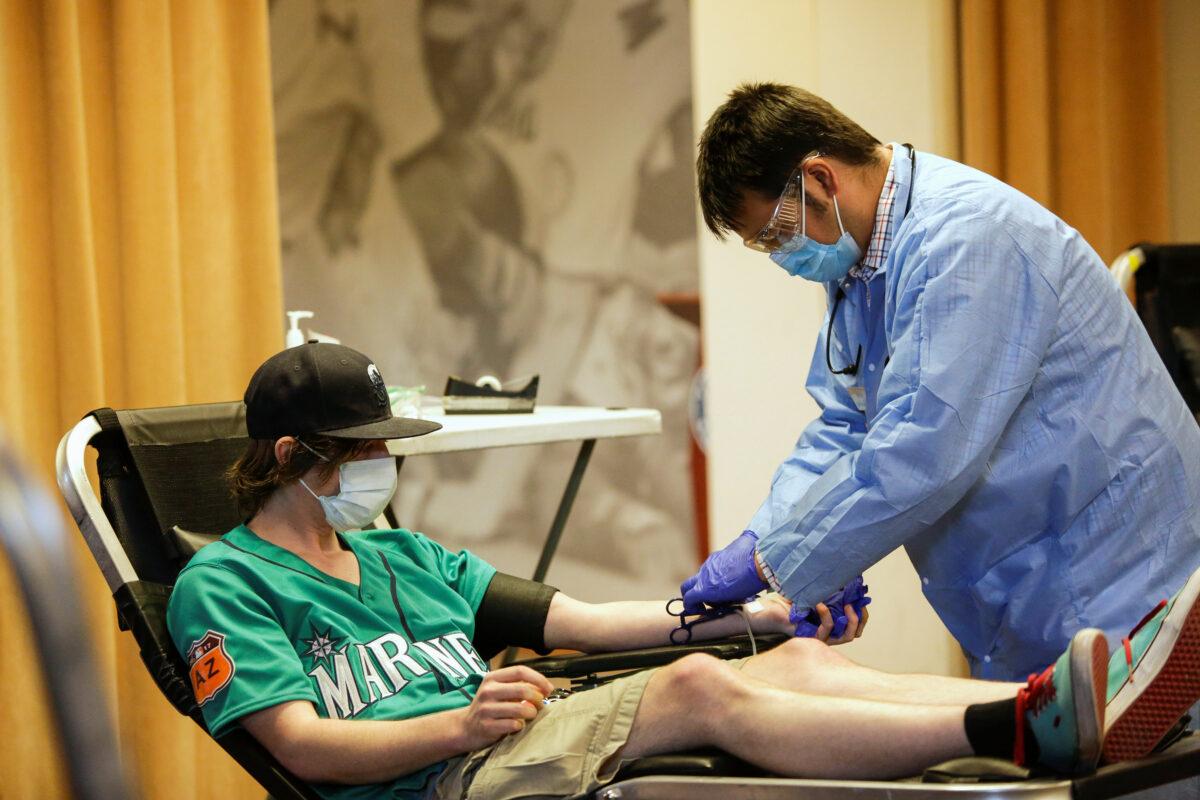 Bloodworks Northwest phlebotomist Niilo Juntunen takes a blood donation from Craig McCall of Tacoma, Wash., during a Pop-Up Blood Drive experience at T-Mobile Park, the stadium of Major League Baseball's Seattle Mariners, as efforts continue to help slow the spread of the COVID-19 in Seattle, on April 13, 2020. (Jason Redmond/Reuters)