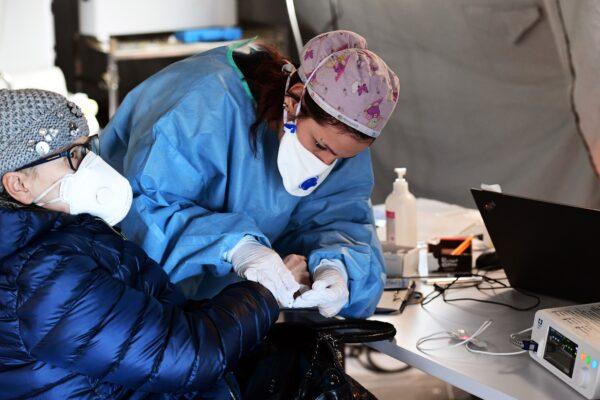 An elderly woman receives assistance in a pre-triage medical tent in front of the Cremona hospital in Cremona, northern Italy, on March 4, 2020. (Miguel Medina/AFP via Getty Images)