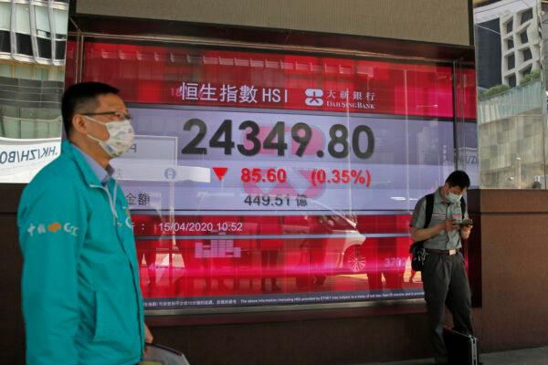 Men wearing masks stand in front of an electronic board showing Hong Kong share index outside a local bank in Hong Kong, on April 15, 2020. (Kin Cheung/AP Photo)
