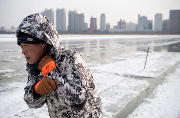 A worker is dragging ice blocks on the frozen Songhua river in Harbin, China, on Dec. 11, 2019. (Noel Celis/AFP via Getty Images)