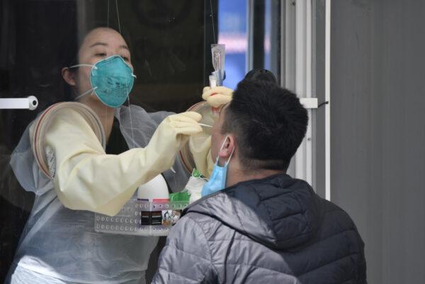 A medical staff member in a booth takes samples from a visitor for the COVID-19 test at a walk-through testing station set up at Jamsil Sports Complex in Seoul on April 3, 2020. (Jung Yeon-je /AFP via Getty Images)