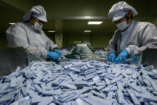 Sample testing devices used in diagnosing COVID-19 are checked on a production line as they are prepared to be included in testing kits for shipment at the SD Biosensor bio-diagnostic company near Cheongju, south of Seoul, on March 27, 2020. (Ed Jones/AFP via Getty Images)