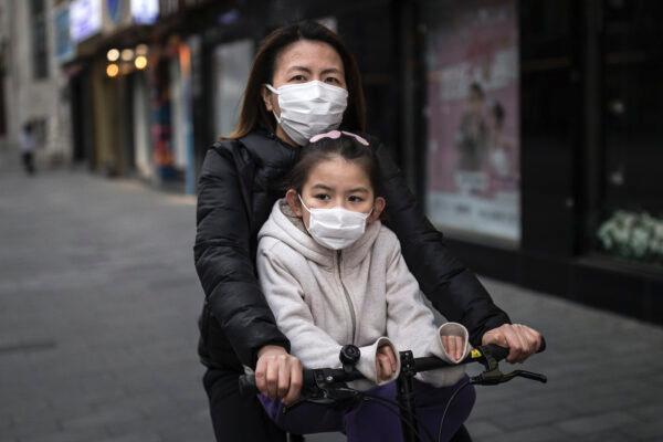 A mother wears a mask as she rides a bike with her daughter in Wuhan, Hubei Province, China, on April 11, 2020. (Getty Images)