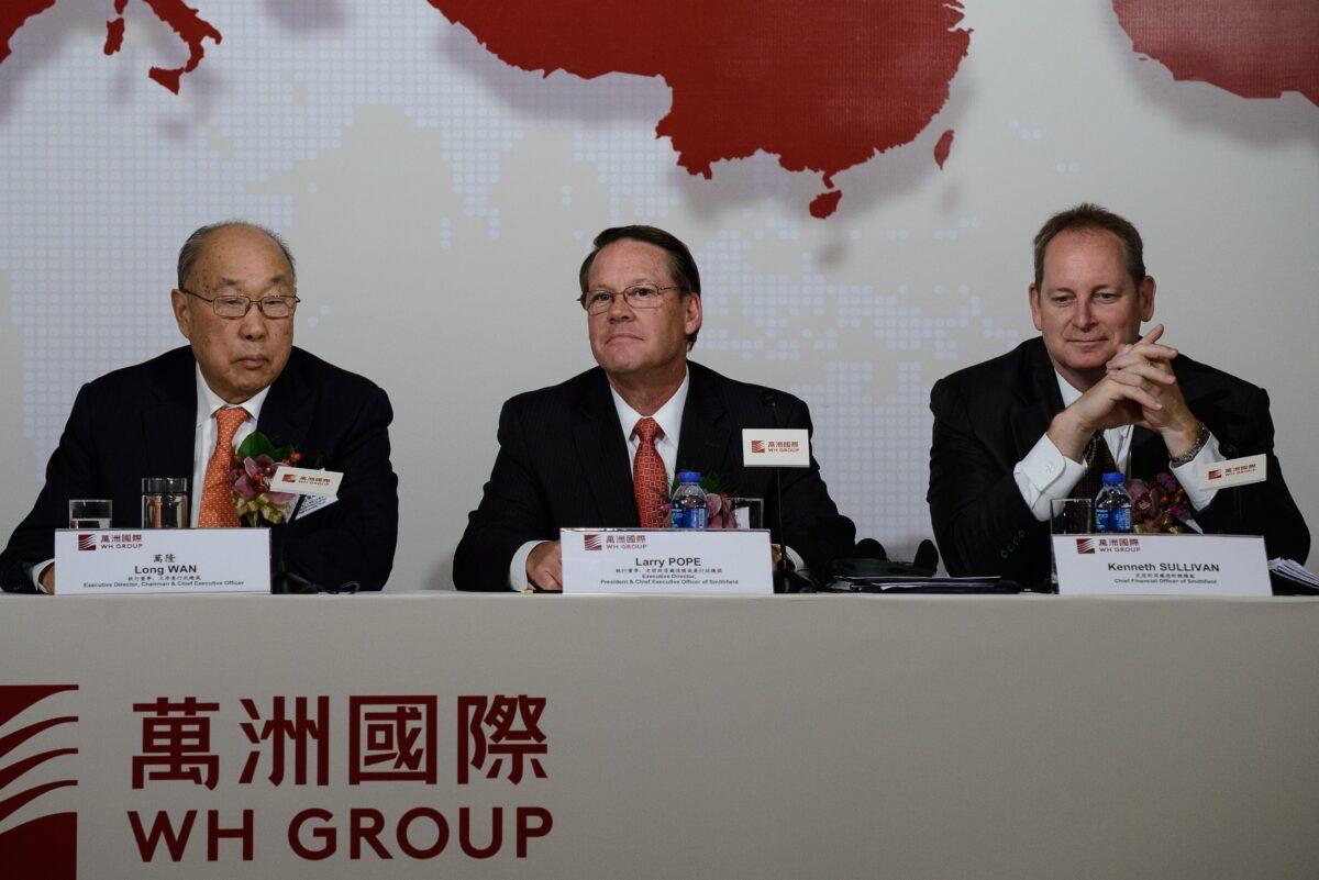 Executive director and chairman of WH Group, Wan Long, executive director and president of Smithfield, Larry Pope, and Smithfield chief financial officer, Kenneth Sullivan attend a press conference in Hong Kong on April 14, 2014. (Philippe Lopez/AFP via Getty Images)