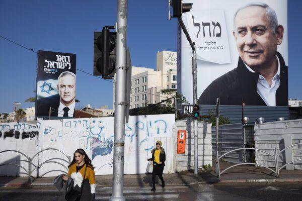 People walk next to election campaign billboards showing Israeli Prime Minister Benjamin Netanyahu (R) and Benny Gantz (L) in Bnei Brak, Israel, on March. 1, 2020. (Oded Balilty/AP Photo)