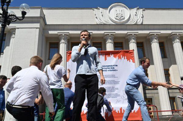 Member of the Ukrainian Parliament, founder of Ukrainian political party 'Golos' (Voice) and rock star Svyatoslav Vakarchuk speaks, as members of his party sign a banner with the headline, "Commitment of deputies candidates of the political party Golos (Voice) to the parliament" during an election campaign rally "Change the Parliament, Change the Country" in front of the parliament building in Kyiv on June 25, 2019. (Sergei Supinsky /AFP via Getty Images)