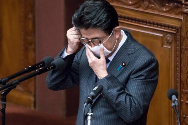 Japan's Prime Minister Shinzo Abe adjusts his face mask as he speaks during an ordinary session at the upper house of parliament in Tokyo, Japan, on April 2, 2020. (Tomohiro Ohsumi/Getty Images)