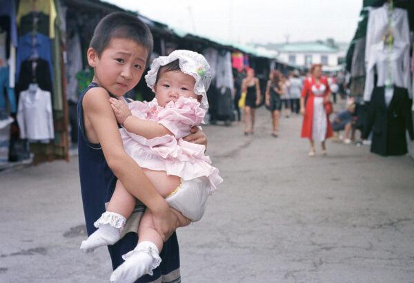 A boy holds his little sister in the Chinese market in the town of Ussuriysk in Russian on September 7, 2000. (Oleg Nikishin/Newsmakers)