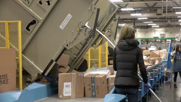 The universal unloader drops packages onto the loading belt for processing at the United States Postal Service in San Francisco on Dec. 16, 2019. (Ilene Eng/The Epoch Times)