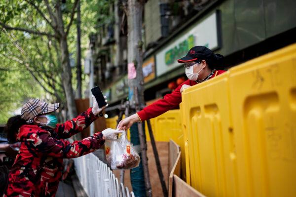 A vendor hands food to a customer over a barricade separating a residential compound in Wuhan, China's central Hubei province on April 6, 2020. (Noel Celis/AFP via Getty Images)