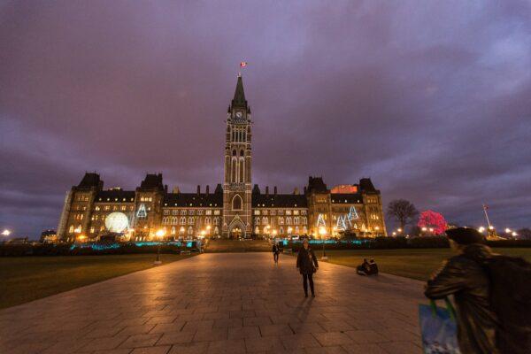 Tourists take pictures in front of the parliament building in Ottawa, Canada on December 4, 2015. (Photo Geoff Robins/AFP via Getty Images)