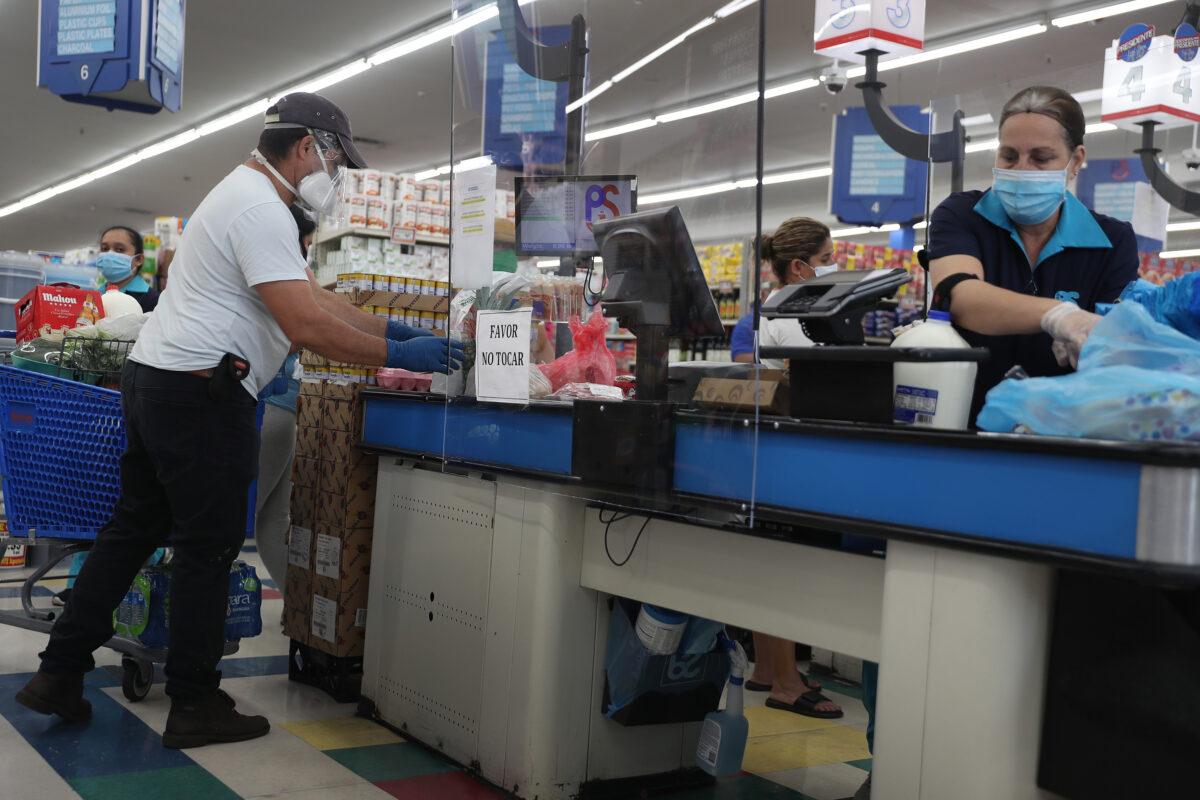 A cashier wears a mask and gloves at the Presidente Supermarket in Miami, Florida, on April 13, 2020. (Joe Raedle/Getty Images)