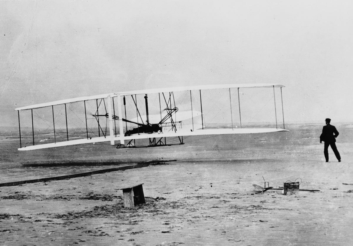 Orville Wright flying a Wright glider at Kill Devil Hills, near Kitty Hawk, N.C. The flight was officially the first sustained, controlled flight by a heavier-than-air craft. Wilbur Wright runs alongside his brother. (Fox Photos/Getty Images)