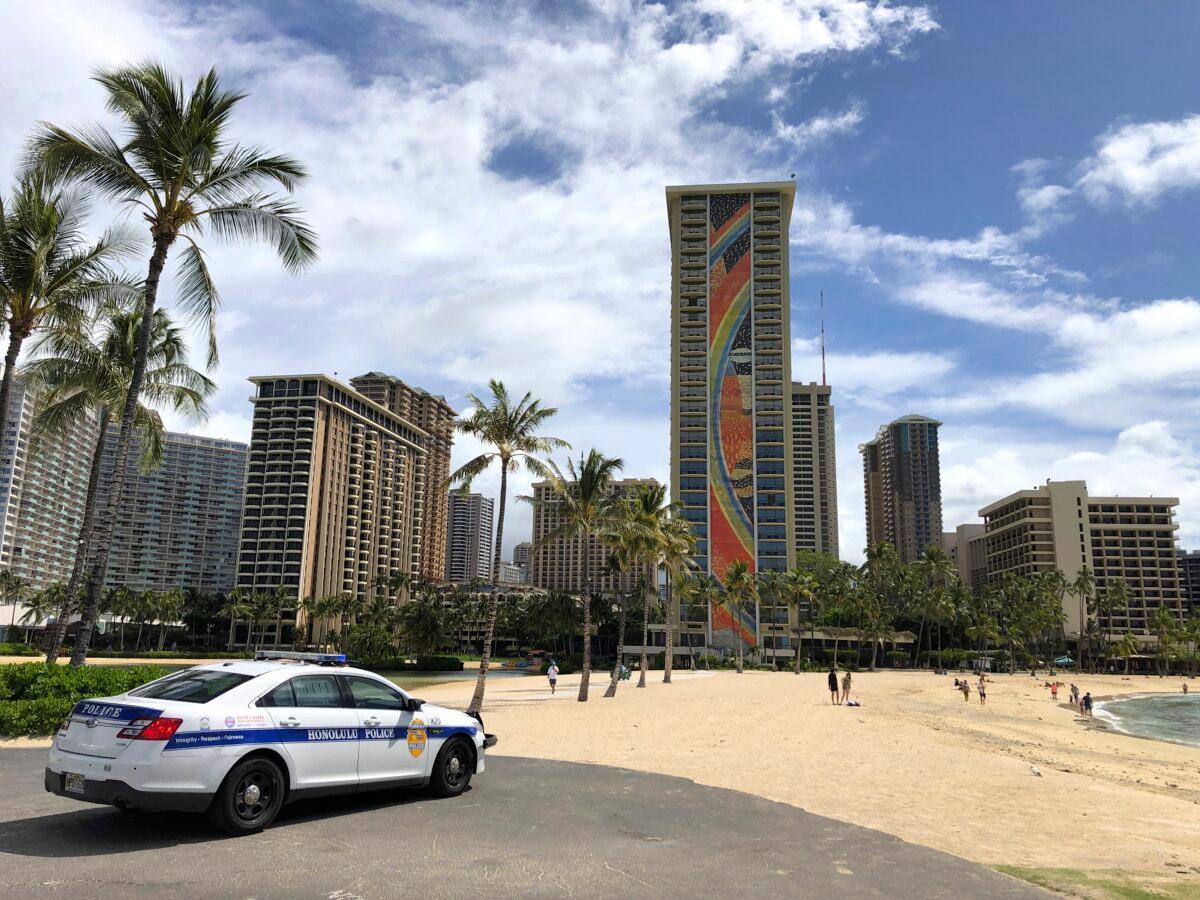 A police officer arrives to tell people to leave Waikiki Beach in Honolulu on March 28, 2020. (Caleb Jones/AP Photo)