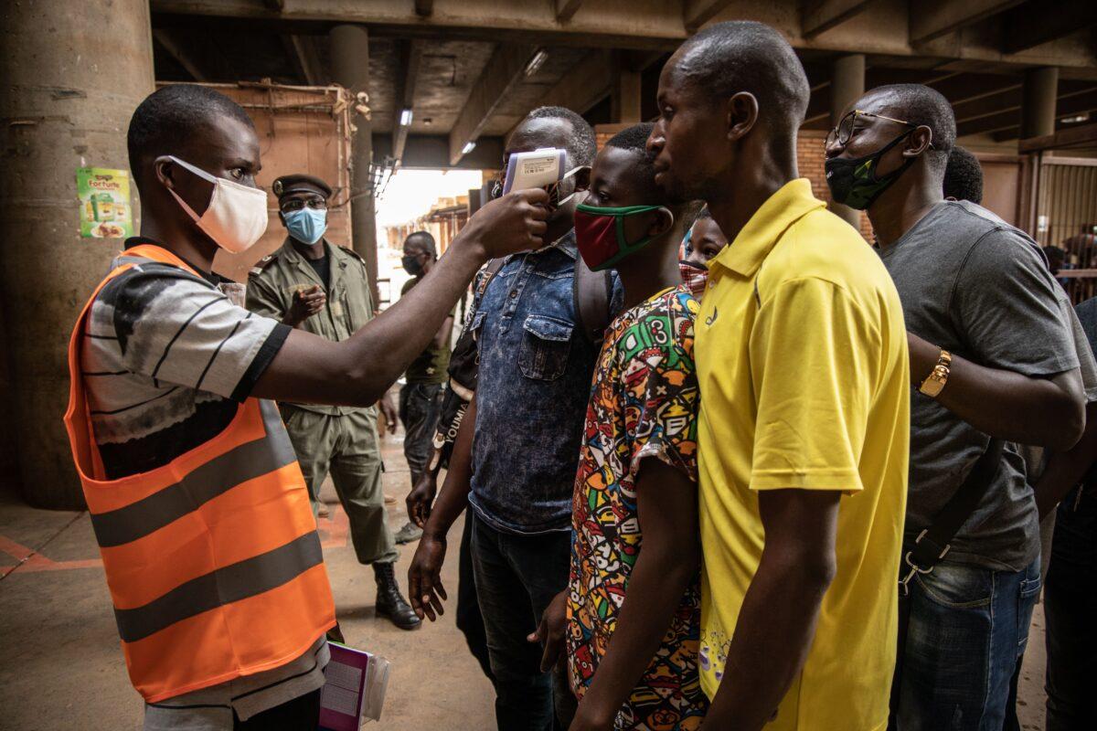 A communal agent measures the body temperature of traders at the opening of Rood Wokos great market in Ouagadougou on April 20, 2020. (Olympia De Maismont/AFP via Getty Images)