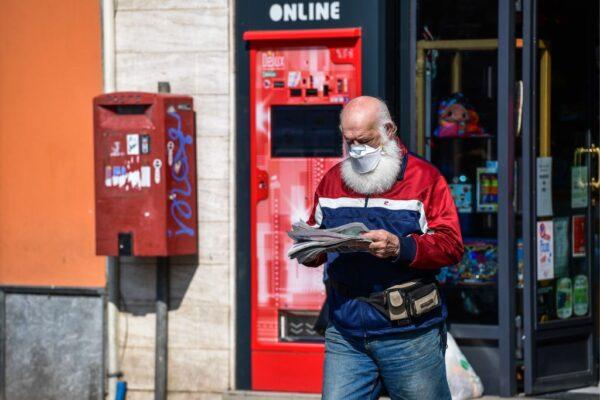 A resident wearing a face mask exits a shop after buying a newspaper in Treviolo, Italy, on April 9, 2020. (Miguel Medina/AFP via Getty Images)
