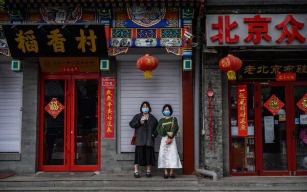 Chinese women wear protective masks as they stand outside closed shops and restaurants near the Forbidden City in Beijing, China on April 19, 2020. (Kevin Frayer/Getty Images)