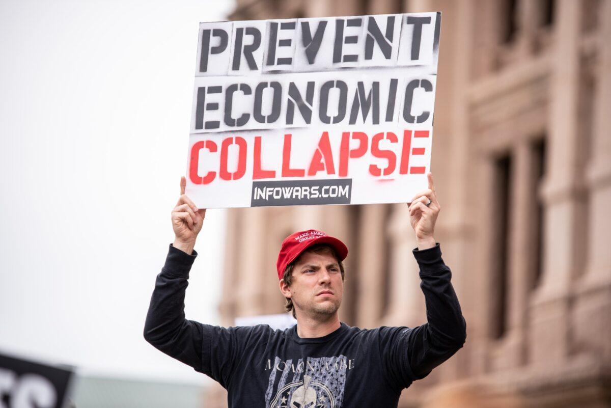 A protester holds up a sign that reads "Prevent Economic Collapse" at the Texas State Capital building in Austin, Texas, on April 18, 2020. (Sergio Flores/Getty Images)