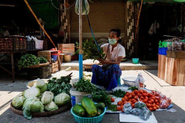 A vegetable vendor, wearing a face mask as a preventive measure against the spread of the COVID-19 novel CCP virus, waits for customers at a street market in Yangon, Burma, on April 21, 2020. (Sai Aung Main / AFP via Getty Images)