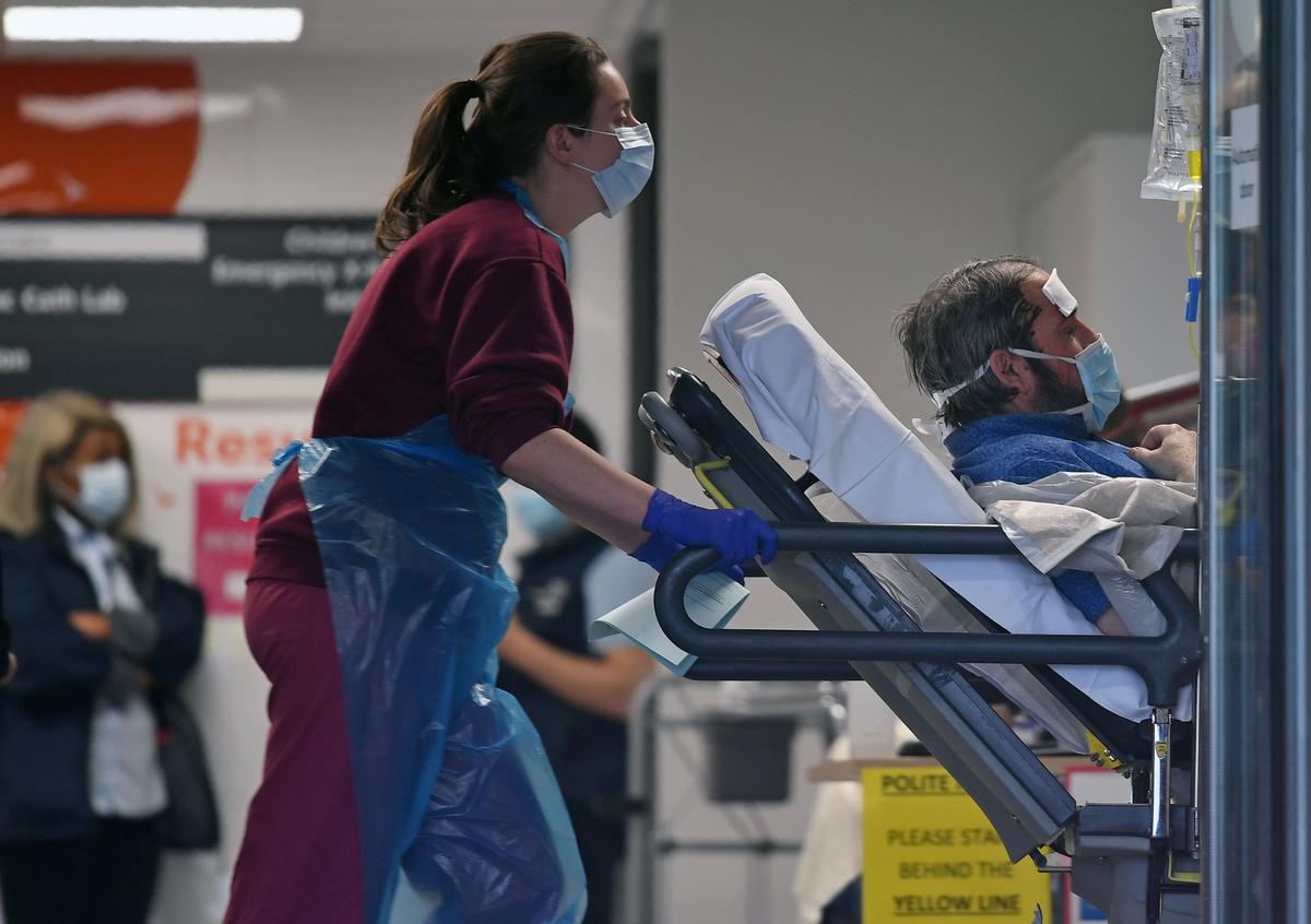 A medical professional in PPE transfers a patient inside St Thomas' Hospital in London, England. (DANIEL LEAL-OLIVAS/AFP via Getty Images)