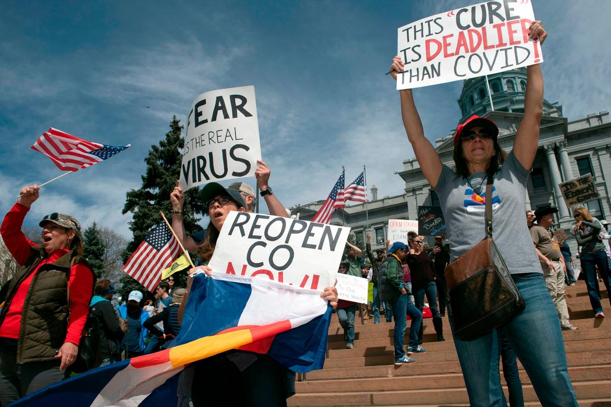 Demonstrators brandish hand-drawn signs in front of the Colorado State Capitol building in Denver on April 19, 2020. (JASON CONNOLLY/AFP via Getty Images)